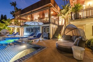 Un edificio de dos pisos con piscina, asientos exteriores y un área de estar techada.