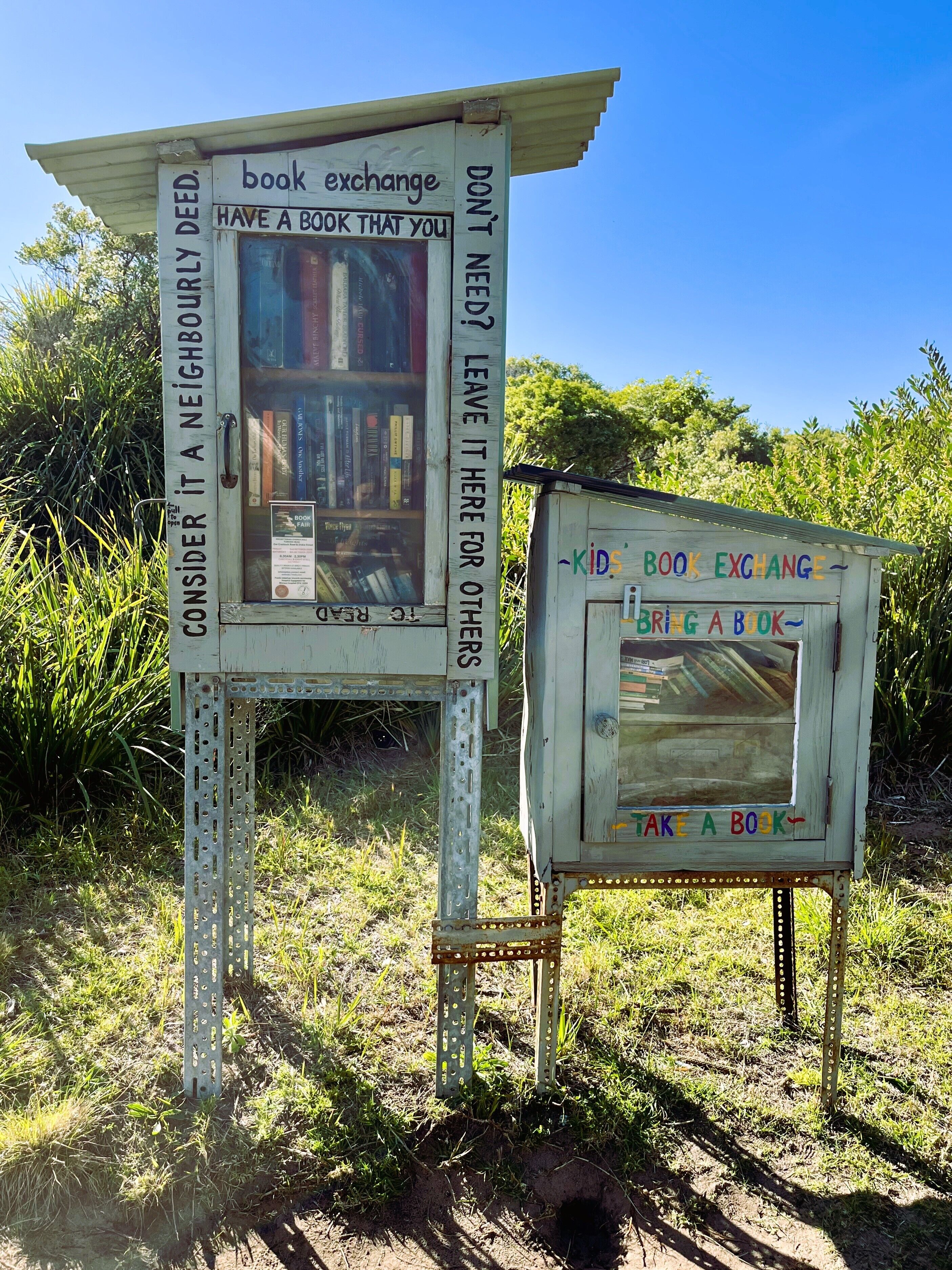 Eine Bücheraustauschstation mit einem Schild, das Besucher dazu auffordert, dies als eine freundliche Geste zu betrachten und ein Buch für andere beizubehalten.