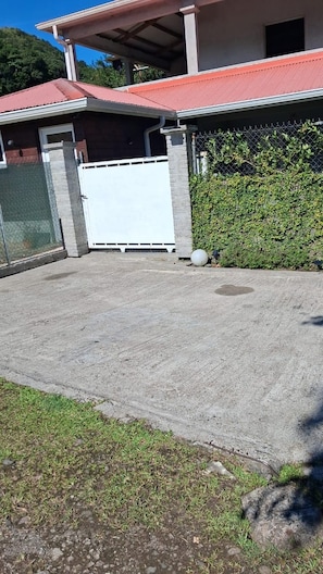 A residential property with a paved driveway, a covered patio area, and a white garage door.