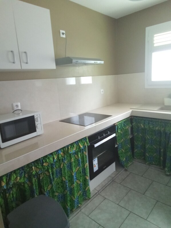 A kitchen with a microwave, stove, and oven. There is a window with blinds.