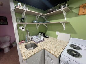 Une cuisine dotée d’un plan de travail en granit, de meubles blancs, d’un évier en acier inoxydable et d’une cuisinière blanche.