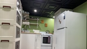 Eine kleine Küche mit weißen Schränken, einem Herd, einem Backofen und einem Kühlschrank.