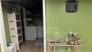 Eine Küche mit grüner Wand, einem rosafarbenen Rollwagen und einem Schild mit der Aufschrift 'BAR RULES'.