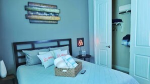 A neatly made bed with a headboard, a bedside table with a lamp, and a wall-mounted artwork. - Spacious 5-bedroom Modern Stay Near - IAH-AIRPORT (Humble)