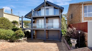 Un immeuble résidentiel de deux étages doté d’un balcon, d’un garage et d’une façade en briques.