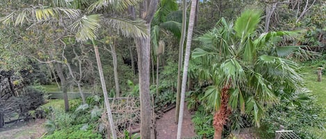 Een balkon met uitzicht op een weelderige tuin met diverse bomen en planten.