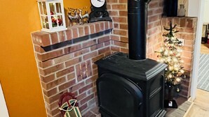 A brick fireplace with a black stove, a white lantern, and a small Christmas tree.