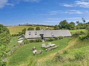 A house with a sloped roof, a fire pit, and outdoor seating.
