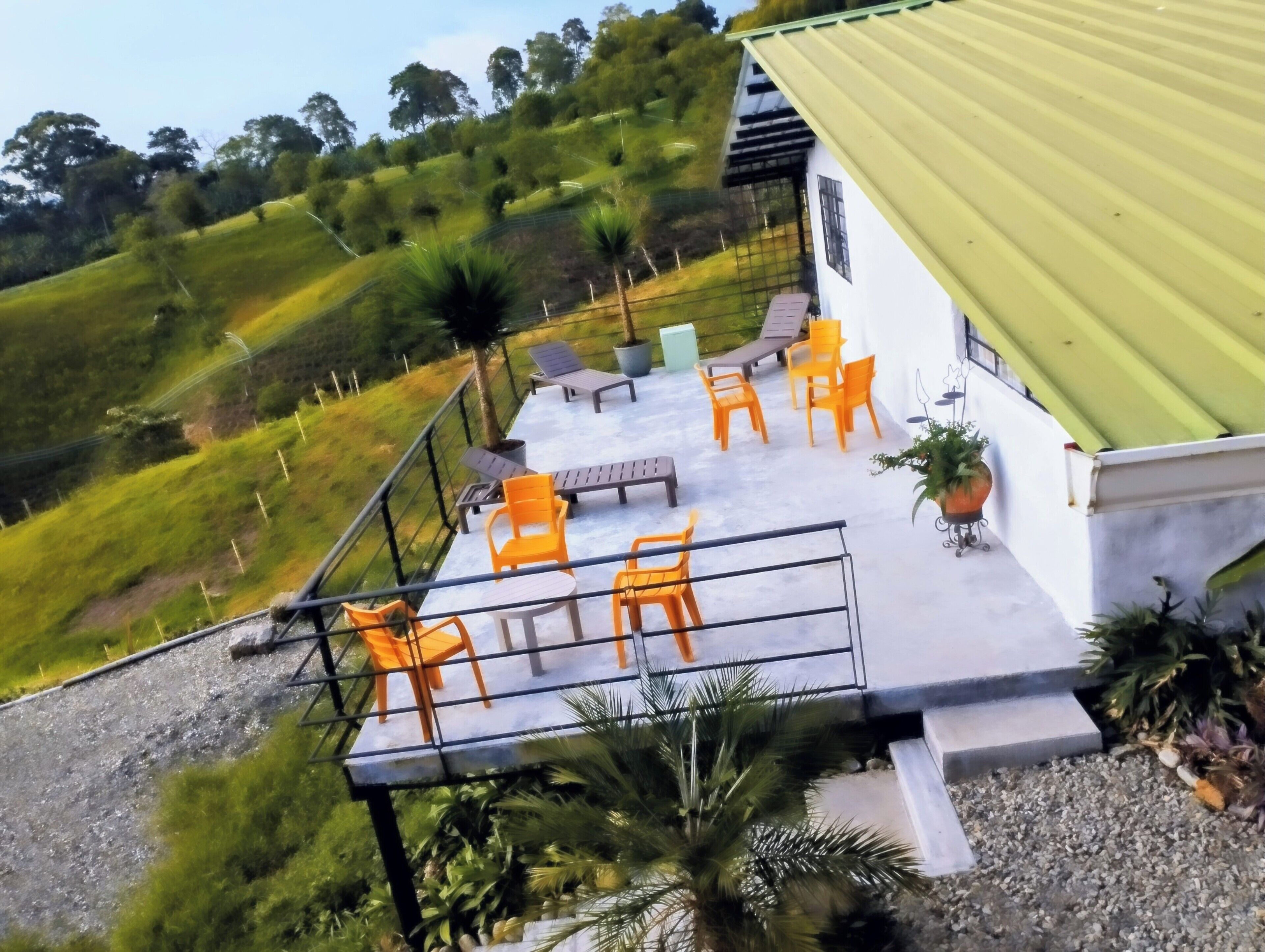 A terrace with outdoor seating and a view of a hilly landscape.