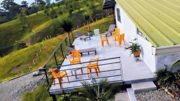 A terrace with outdoor seating and a view of a hilly landscape.