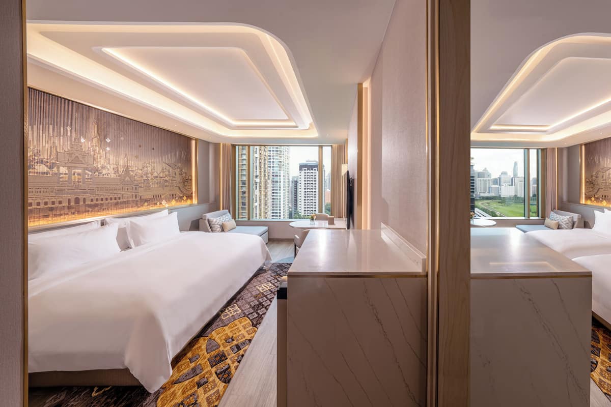 A modern hotel room with a large bed, a small desk, and a view of the cityscape.