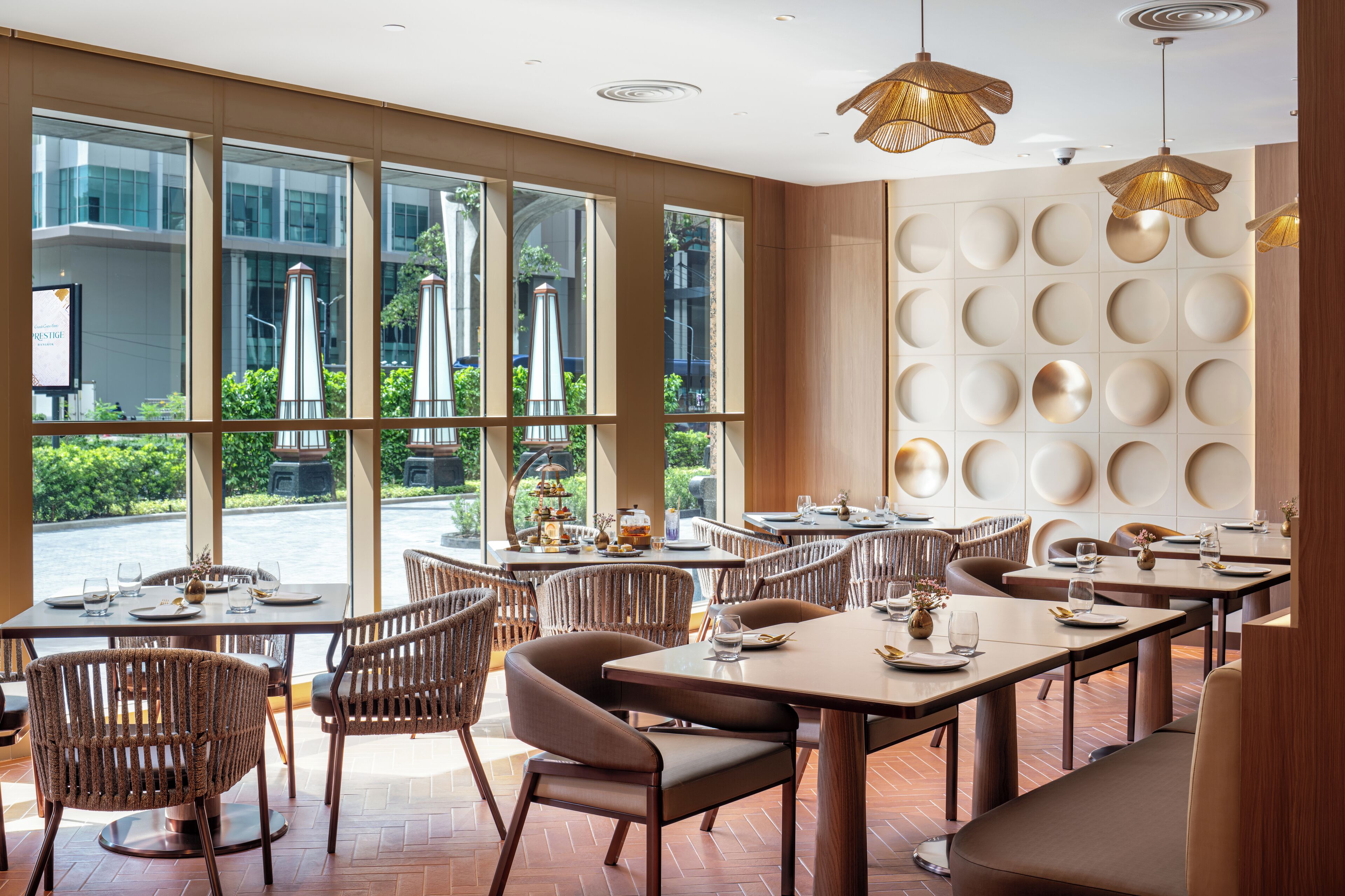 Un restaurante con amplios ventanales, sillas de mimbre y una decoración interior moderna.
