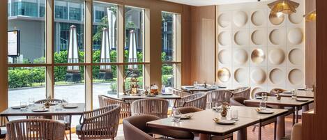 Un restaurante con amplios ventanales, sillas de mimbre y una decoración interior moderna.