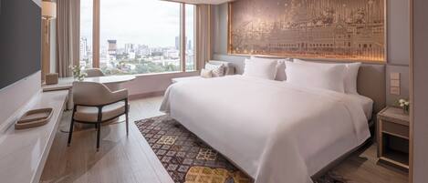 A modern hotel room with a large bed, a desk, and a view of the city.