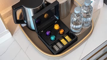A tray with a coffee maker, two water bottles, and a set of colorful drinkware.
