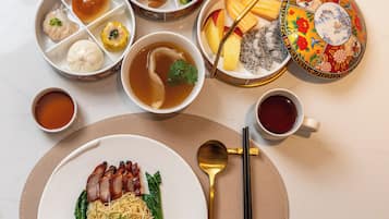 A variety of dishes including noodles, dumplings, and soup, arranged on a table with chopsticks and a spoon.