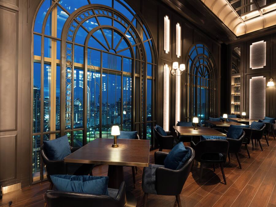 A restaurant with a view of the cityscape, featuring tables and chairs arranged for dining.