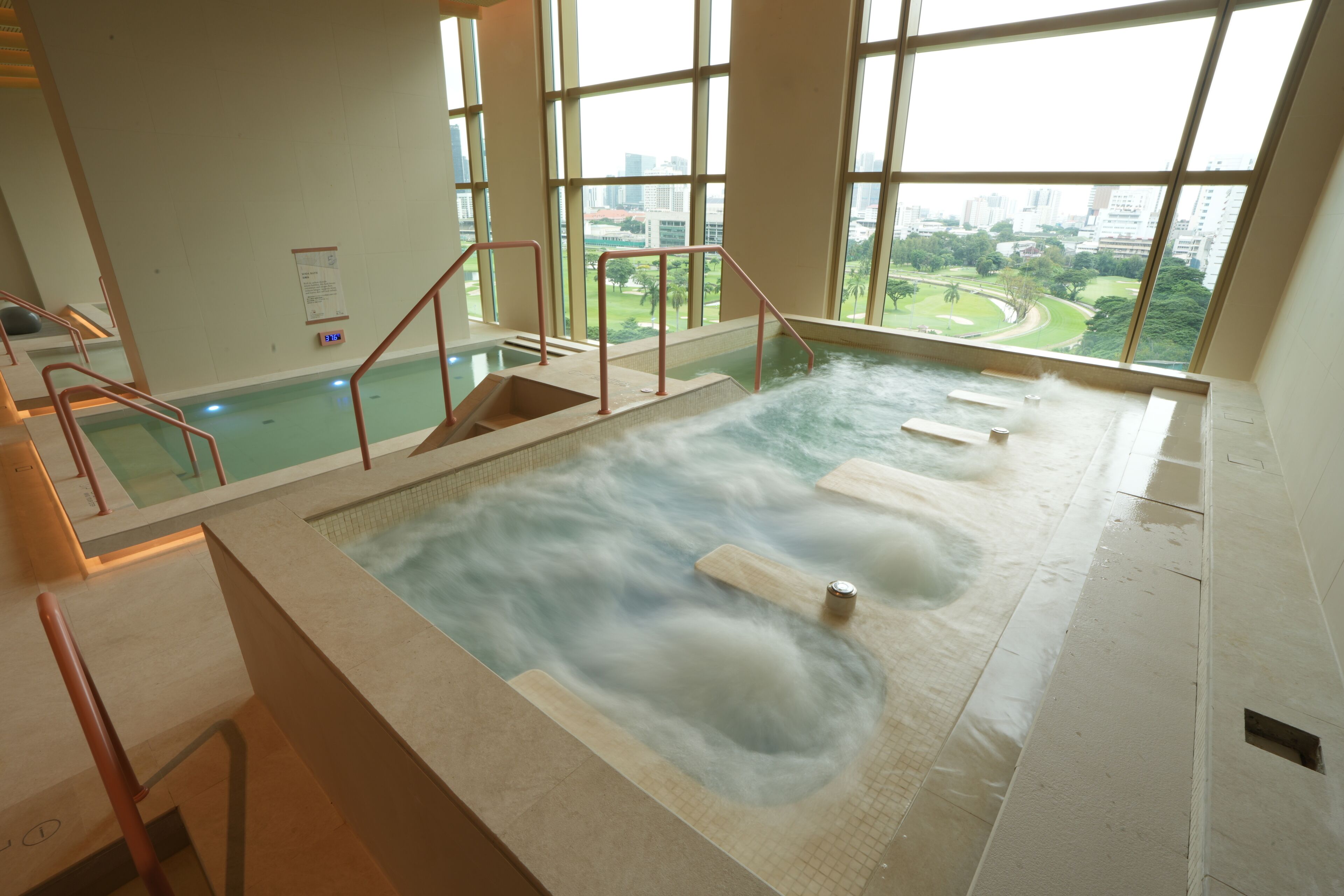 Piscina interior con vistas a un paisaje urbano a través de amplias ventanas.
