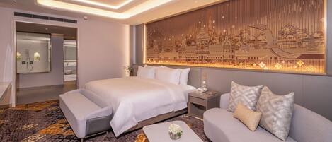 Una habitación de hotel moderna con una cama grande, un sofá, una mesita y un panel decorativo en la pared.