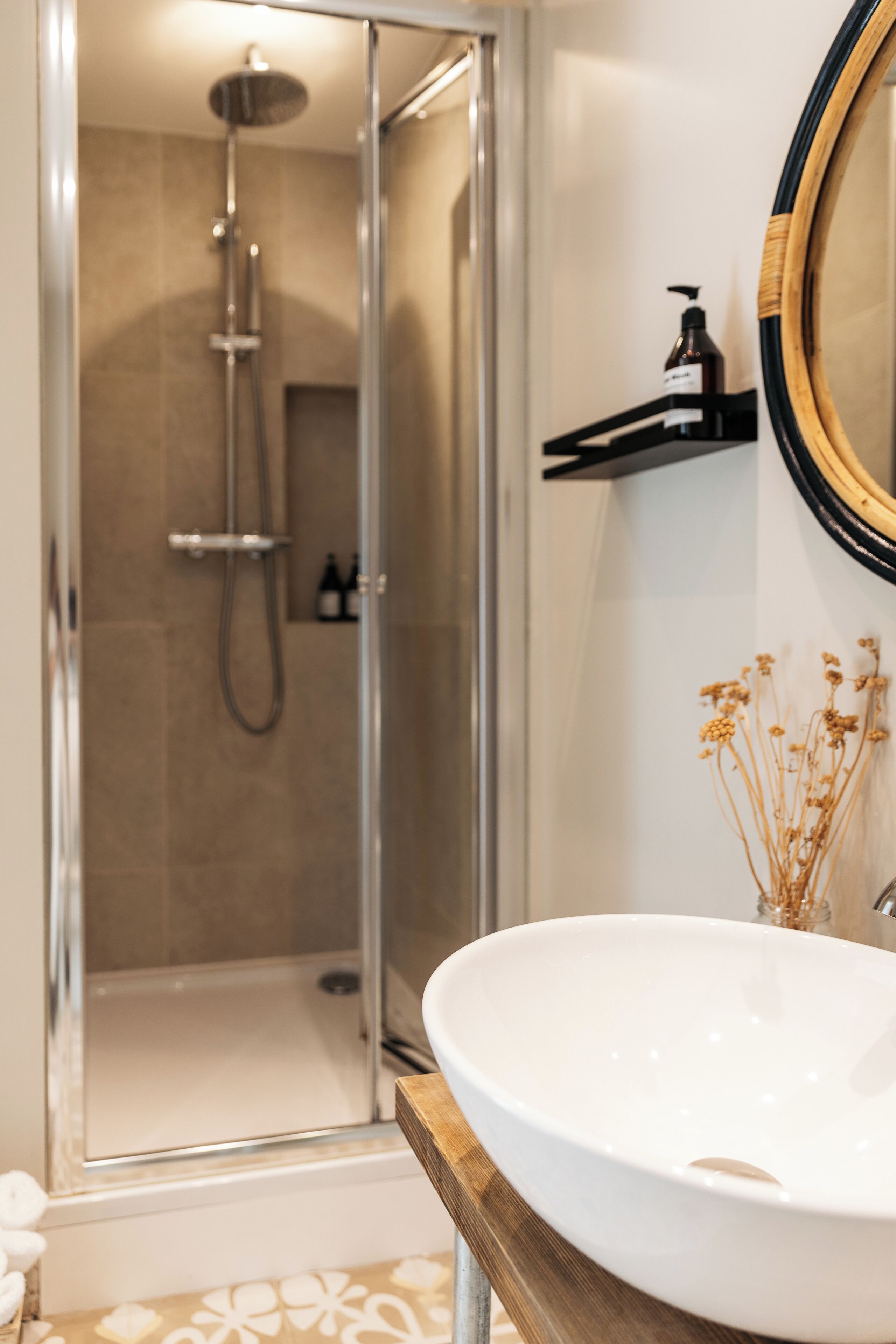 A bathroom with a glass-enclosed shower, a white sink, and a mirror with a wooden frame.