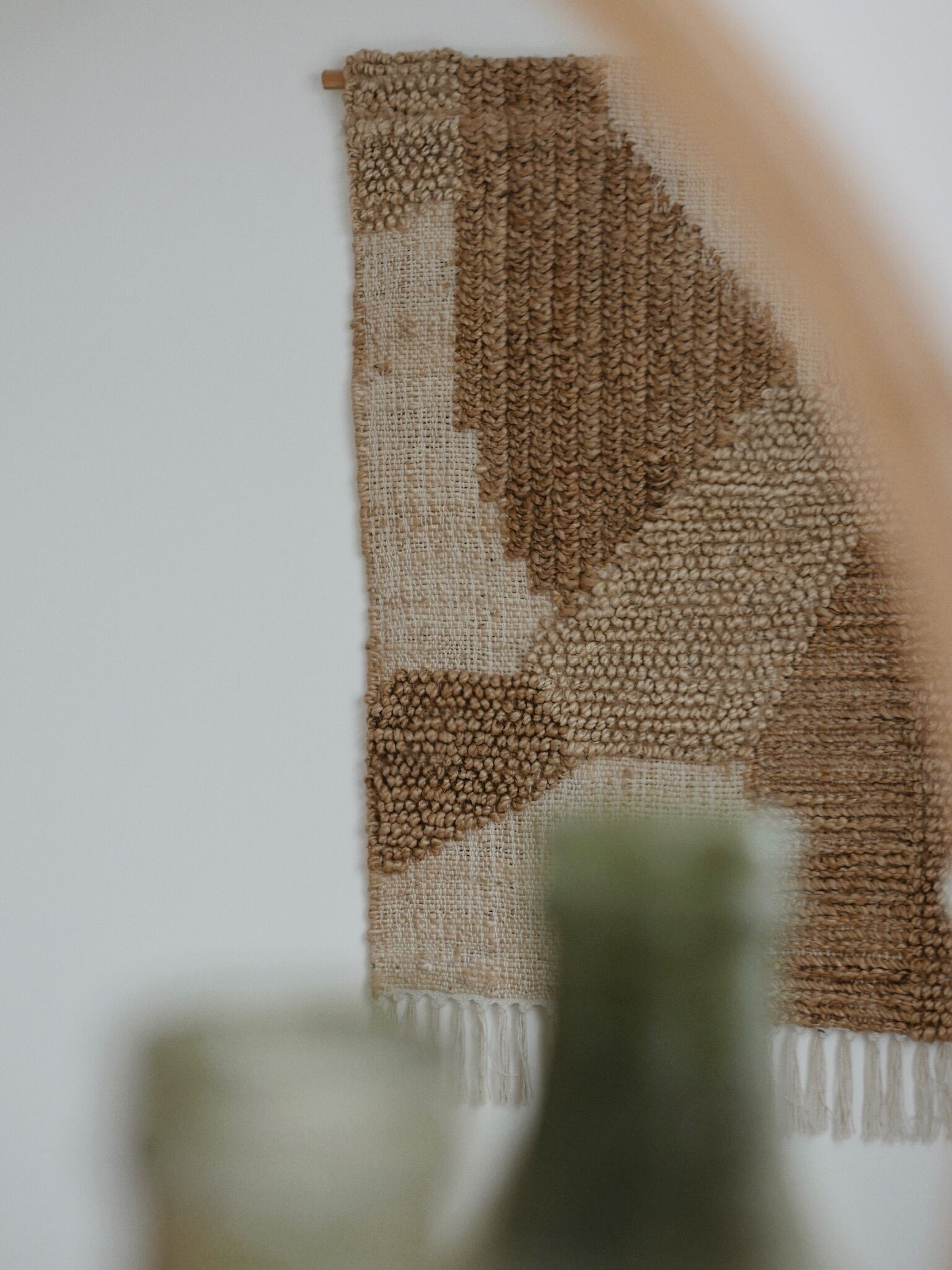 A close-up of a woven textile with a geometric pattern, possibly a wall hanging or tapestry.