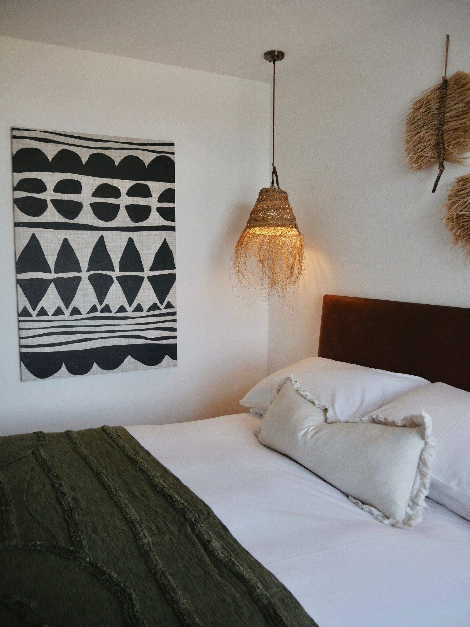 Un dormitorio con cama, lámpara colgante y una obra de arte en la pared.
