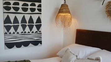 Un dormitorio con cama, lámpara colgante y una obra de arte en la pared.