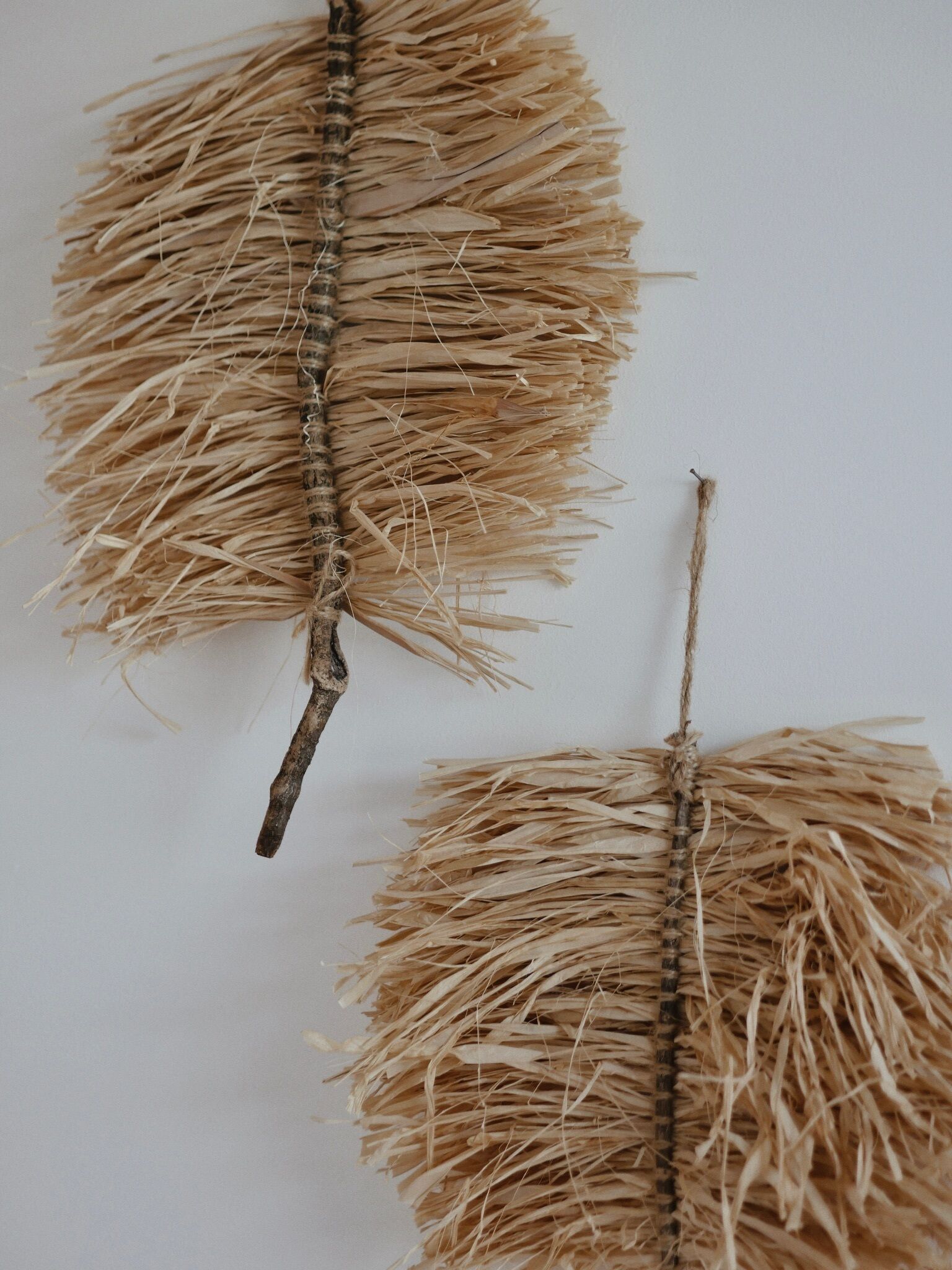 Een detailopname van een rustieke wandhanger, geweven van stro en touw, met een natuurlijke, aardse kleurenpalet.