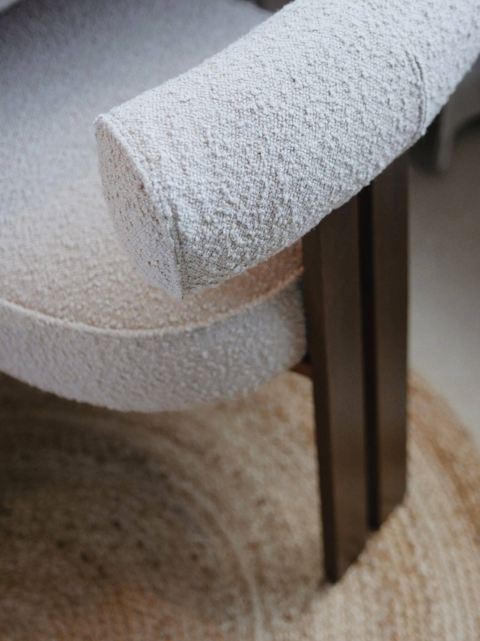 A close-up of a chair with a textured fabric and a wooden leg.