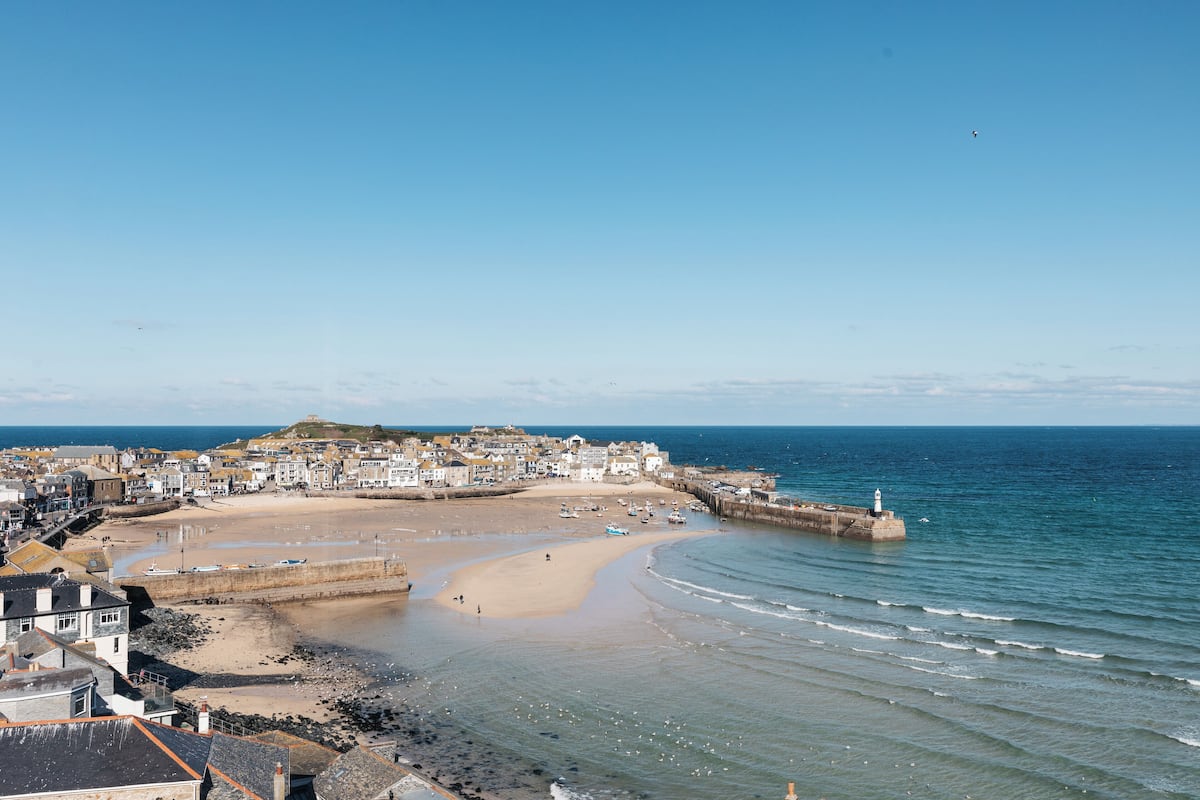 A coastal town with a sandy beach, a lighthouse, and a sea wall.