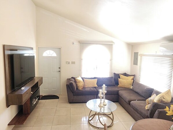 A living room with a television, a sofa, a coffee table, and a door.