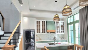 Une cuisine moderne dotée d’un îlot central, de chaises en bois et de luminaires suspendus.