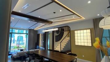 Un comedor moderno con una mesa larga y sillas, una escalera y ventanas amplias que dejan entrar luz natural.