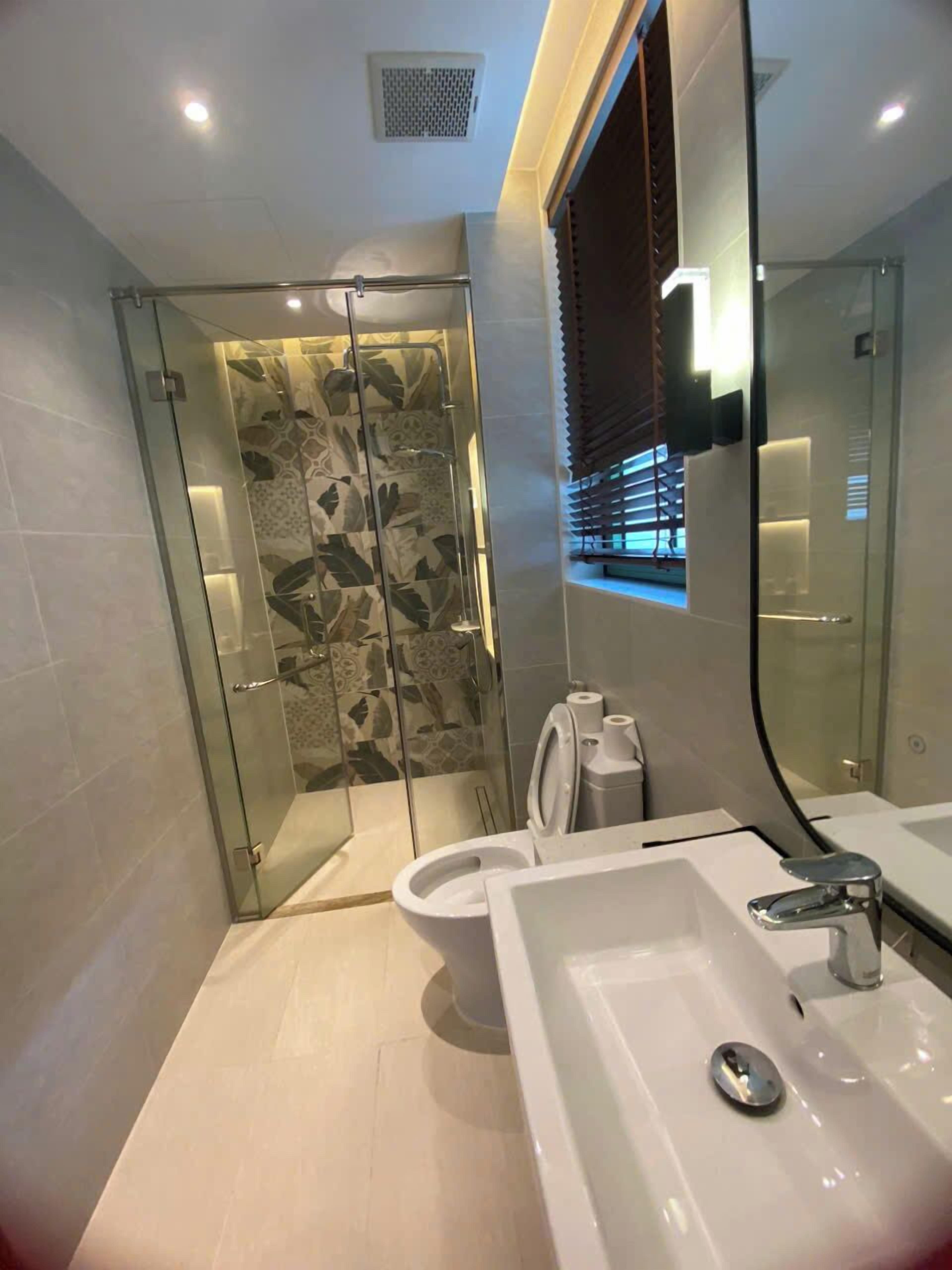 A modern bathroom with a glass-enclosed shower, a large mirror, and a white sink.