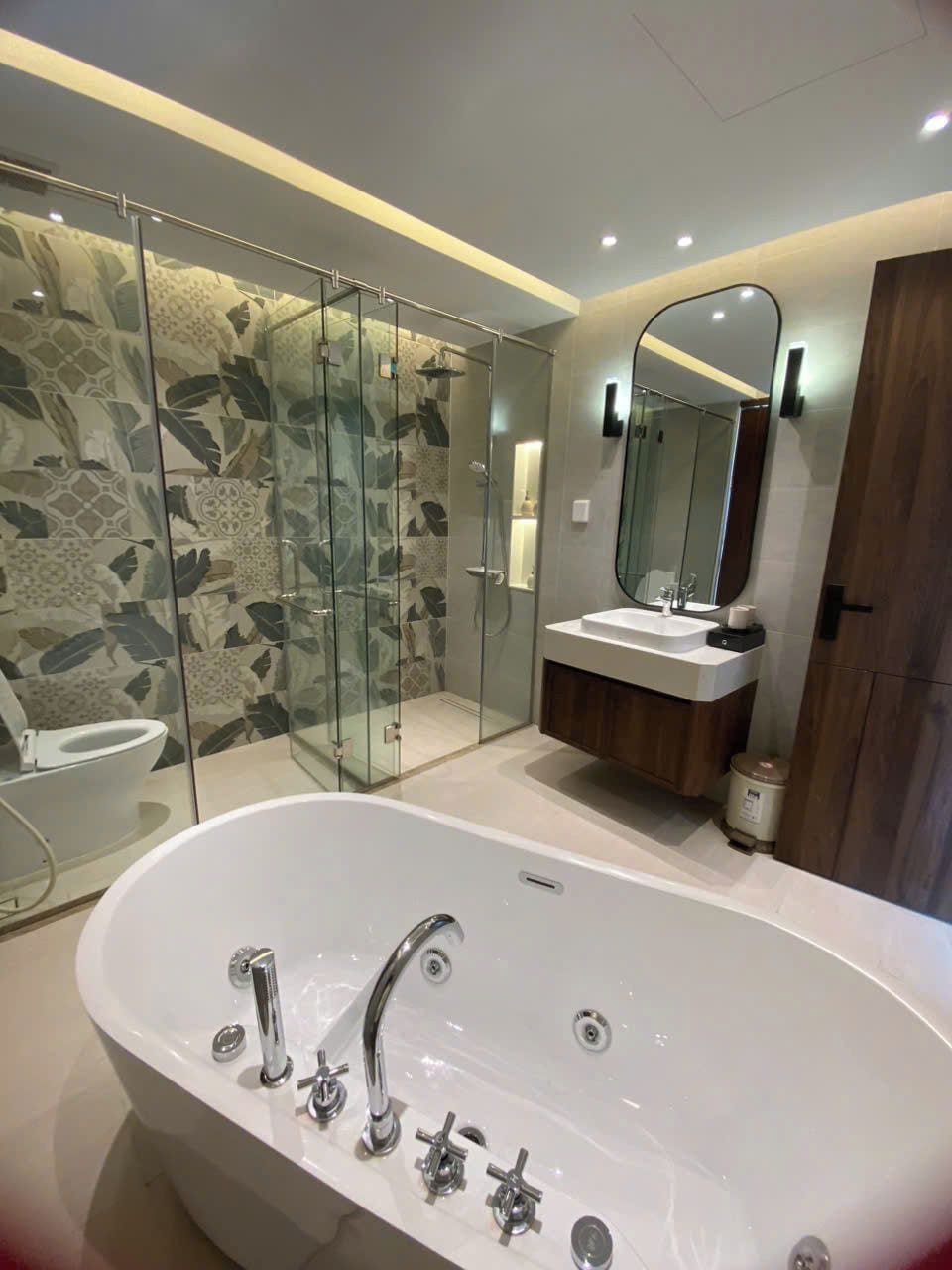A modern bathroom with a freestanding bathtub, a glass-enclosed shower, and a vanity with a mirror.
