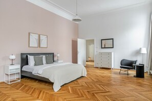 Een moderne slaapkamer met een bed, nachtkastjes, een dressoir, een stoel en een spiegel.