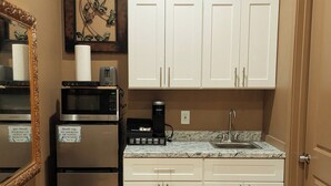 A compact kitchen with white cabinets, a microwave, a coffee maker, and a sink. - Suite #2 Full Private Studio - Brand New! (Clovis)