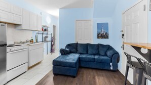 A compact living space with a kitchenette, a blue sofa, and a dining area.