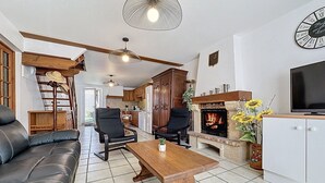 Un salon spacieux avec une cheminée, un canapé en cuir, une table basse en bois et un téléviseur posé sur un meuble.