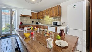 Une cuisine moderne avec des meubles en bois, un grand îlot central doté d’un plateau en verre et un four à micro-ondes encastré.