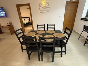 A dining area with a round table, black chairs, and woven placemats.