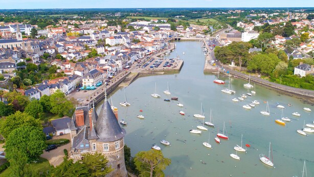 A coastal town with a prominent tower, a marina with numerous boats, and a mix of residential and commercial buildings along the waterfront. - Les Musardises by Interhome (Pornic)