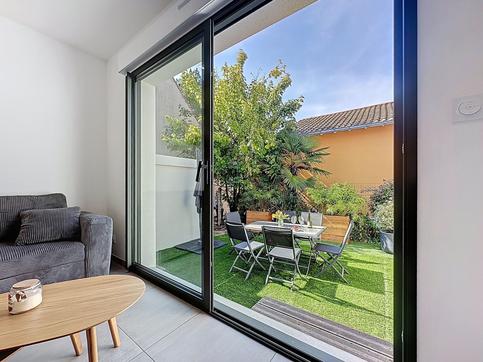 A modern living room with a sliding glass door leading to a well-maintained garden.
