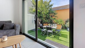 A modern living room with a sliding glass door leading to a well-maintained garden. - Les Musardises by Interhome (Pornic)