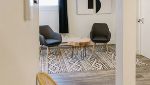 Un interno moderno con un soffitto in legno, un tappeto a motivi bianco e nero e due sedie.