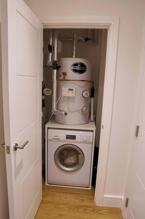 A laundry room with a washing machine and a water heater. - 1 Bed Apartment- Sleeps 2, Parking, Pets Allowed (Birmingham)
