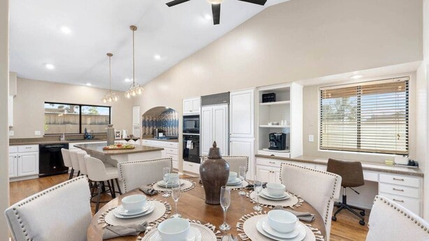 A modern kitchen with white cabinets, a dining area with a round table set for four, and a large vase centerpiece. - Glendale Paradise | Pool | Pickleball | Putt-Putt (Glendale)