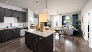 A modern kitchen with dark cabinets, a granite countertop, and pendant lighting. - Stylish Resort Oasis: 5* Location, Pool, Gym, Pkg! (San Antonio)