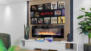 Ein modernes Wohnzimmer mit einem Flachbildfernseher, der über einer weißen Unterhaltungsecke an der Wand befestigt ist.