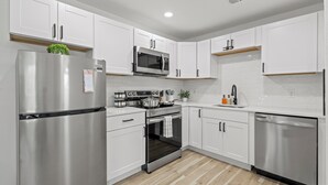 Une cuisine moderne avec des armoires blanches, des appareils en acier inoxydable et un plancher en bois.